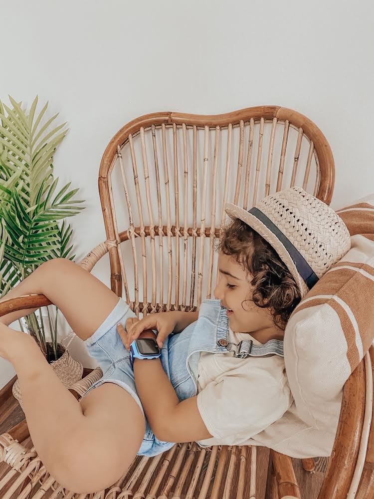 Dreng slapper af i stol og tjekker sit Xplora smartwatch