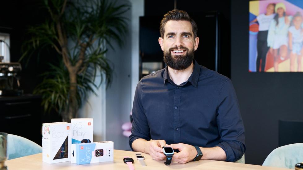 Sten kirkbark manden bag Xplora og vision om barnets første mobiltelefon. Smartwatches til børn ligger på bordet