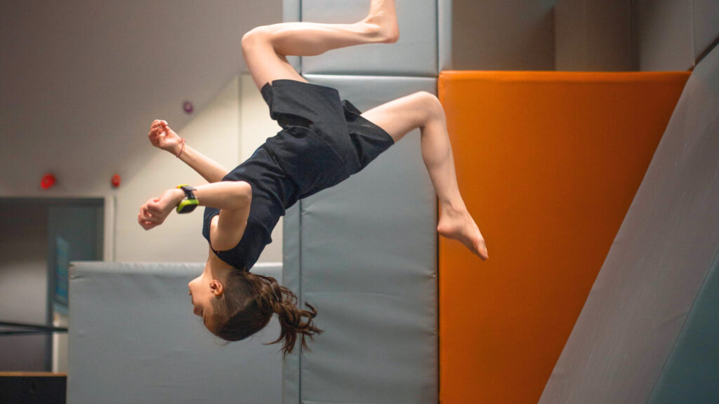 Modigt barn laver en salto med et xplora x6play smartwatch. Selvtillid til børn kommer med den rette hjælp.